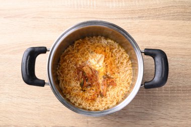 Kore baharatlı hazır şehriye çorbası kimchi ve yumurta ile ahşap arka planda sıcak demlik, masa üstü görünümü