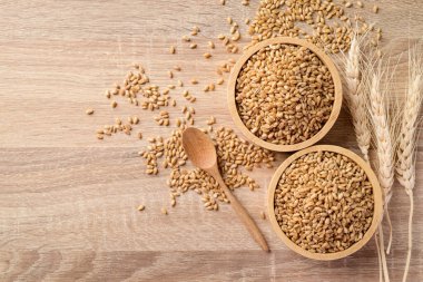 Tahta zemin üzerinde kepekli tahıl, yemek malzemeleri, masa üstü manzarası.