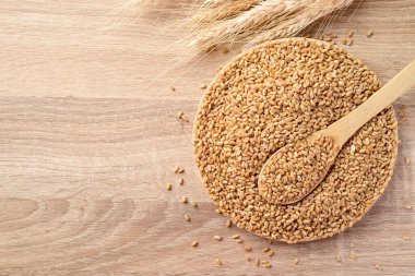 Tabakta tahıllı tahıl, ahşap kaşık, yiyecek malzemeleri, masa üstü manzarası.