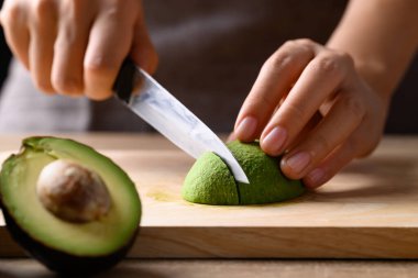 Olgun hass avokado meyvesi, elinde bıçak, tahtadan kesme, sağlıklı beslenme.