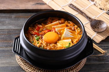 Kore baharatlı şehriye çorbası, kimchi, tofu, yumurta ve mantar Kore taş kasesinde.