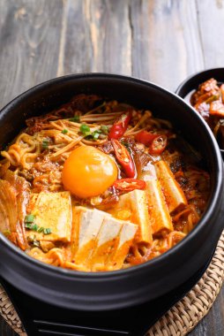 Kore baharatlı şehriye çorbası, kimchi, tofu, yumurta ve mantar Kore taş kasesinde.