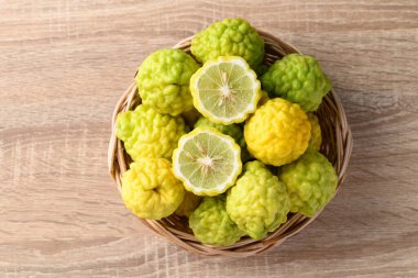 Ahşap arka planda sepetteki kaffir limon meyvesi, Tayland mutfağında organik malzemeler, güzellik ve kozmetik.