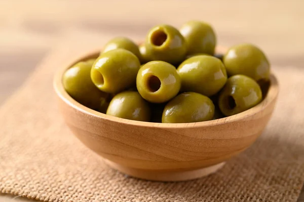 Pickled olives, Pitted green olives in wooden bowl