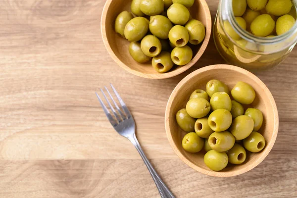 Pickled olives, Pitted green olives in wooden bowl, Table top view