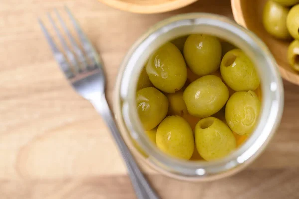Pickled olives, Pitted green olives in glass jar, Table top view