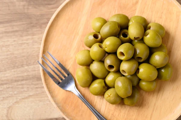 Pickled olives, Pitted green olives on wooden plate with fork