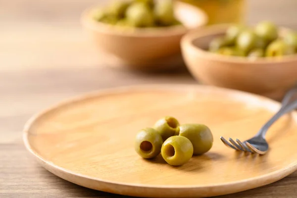 Pickled olives, Pitted green olives on wooden plate
