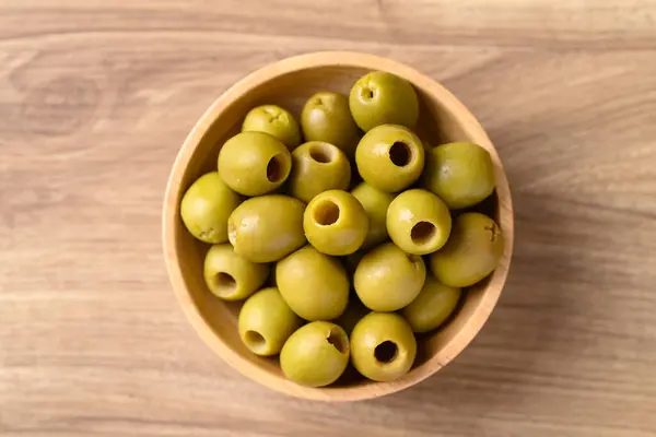 Pickled olives, Pitted green olives in bowl on wooden background, Table top view