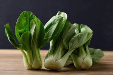 Siyah arkaplan ve organik sebzelerle ahşap masa üzerinde bok choy veya Pak choi (Çin lahanası)