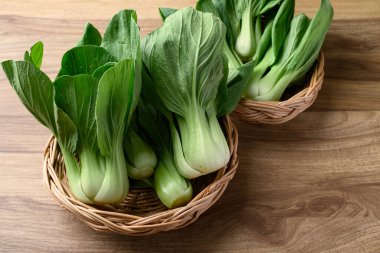 Tahta masa üzerindeki sepetin içinde bok choy veya Pak choi (Çin lahana), organik sebzeler