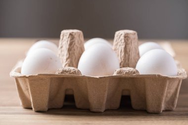 Tahta masadaki kağıt tepside, çiftlikten gelen organik beyaz leghorn yumurtası.