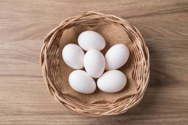 Serbest çiftlikten gelen organik beyaz leghorn yumurtası ahşap masanın üzerindeki sepetin içinde.