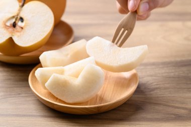 Bir parça Asya armut meyvesi ya da ahşap kasede yemeye hazır Nashi armudu.