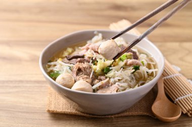 Tahta zemin üzerinde domuz etli erişte çorbası, Tayland eriştesi çorbası.