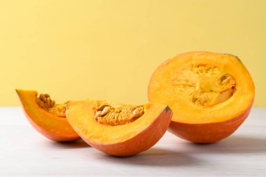 Beyaz üzerine turuncu Hokkaido kabağı, sarı arka plan, sonbahar sebzeleri