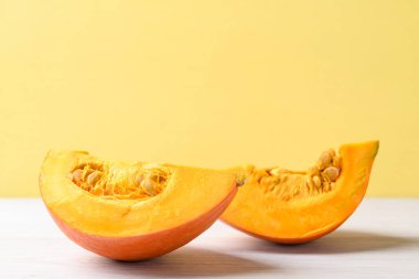 Beyaz üzerine turuncu Hokkaido kabağı, sarı arka plan, sonbahar sebzeleri