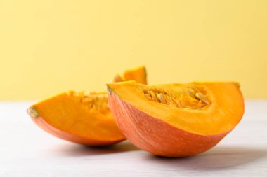 Beyaz üzerine turuncu Hokkaido kabağı, sarı arka plan, sonbahar sebzeleri