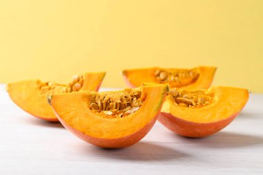 Beyaz üzerine turuncu Hokkaido kabağı, sarı arka plan, sonbahar sebzeleri