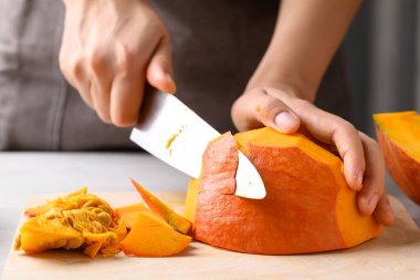 Portakal rengi Hokkaido kabağı, soymak için elinde bıçak, ev yapımı yemek.