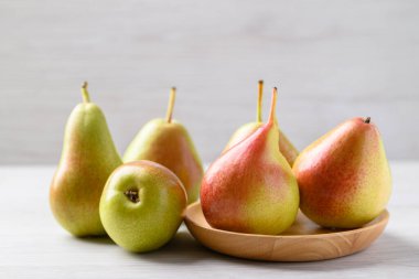 Fresh pear fruit on wooden plate with white table
