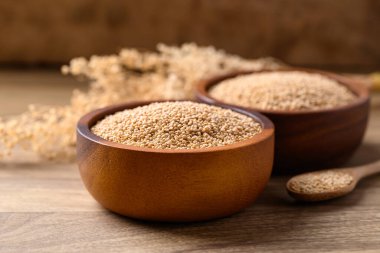 Brown quinoa seed in bowl with spoon on wooden background, Healthy food ingredient