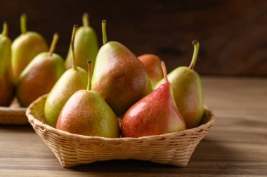 Fresh pear fruit in natural basket on wooden background