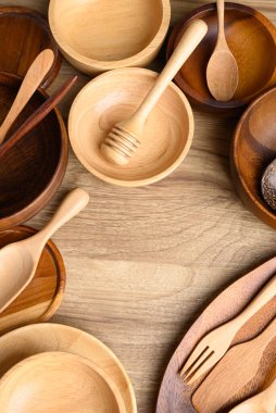 Mutfak aletleri, ahşap kase, tabak, tabak ve kaşık ahşap arka planda, masa üstü görünümü.