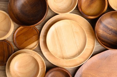 Mutfak gereçleri, ahşap kase, tabak, tabak ve bardak altlıkları ahşap arka planda, masa üstü görünümü.