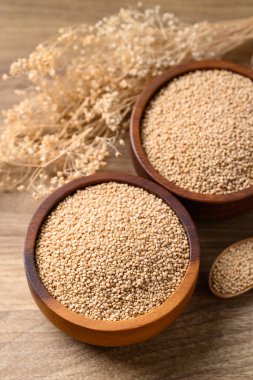 Brown quinoa seed in bowl with spoon on wooden background, Healthy food ingredient