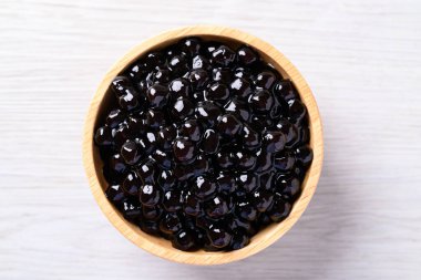 Siyah tapyoka incileri ya da beyaz masadaki ahşap kasede boba, köpük çayının içeriği, üst manzara.