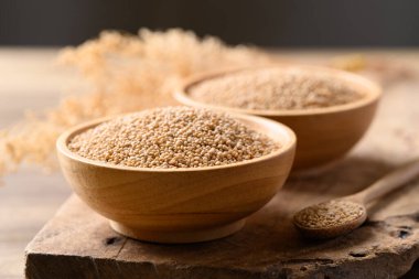 Brown quinoa seed in bowl with spoon on wooden background, Healthy food ingredient