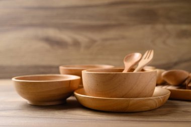 Mutfak gereçleri, ahşap kase, tabak ve kaşık ahşap arka planda.