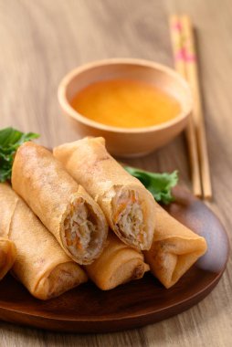 Kabak, havuç ve cam erişteyle doldurulmuş Asya usulü kızarmış börek ahşap zemin üzerinde sos ile yenir.