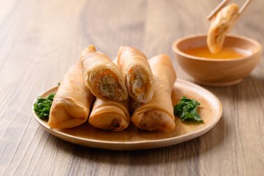 Kabak, havuç ve cam erişteyle doldurulmuş Asya usulü kızarmış börek ahşap zemin üzerinde sos ile yenir.