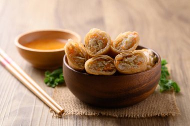 Kabak, havuç ve cam erişteyle doldurulmuş Asya usulü kızarmış börek ahşap zemin üzerinde sos ile yenir.