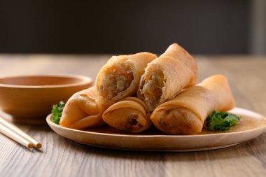 Kabak, havuç ve cam erişteyle doldurulmuş Asya usulü kızarmış börek ahşap zemin üzerinde sos ile yenir.