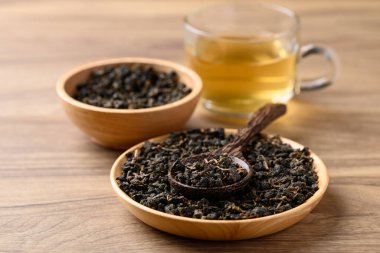 Kurutulmuş Oolong çay yaprakları ve ahşap arka planda sıcak çay.