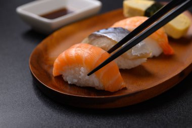 Nigiri suşi somonu, uskumru, karides ve tatlı yumurta (tamago) çubuklarla yenen ahşap tabakta, Japon yemeği.