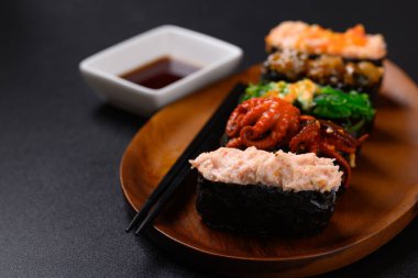 Gunkan maki suşisi ahşap tabakta yemek çubuğu ve sos, Japon yemeği.