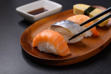 Nigiri suşi somonu, uskumru, karides ve tatlı yumurta (tamago) çubuklarla yenen ahşap tabakta, Japon yemeği.