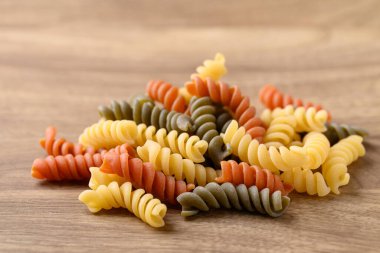 Tahta arka planda sarı, turuncu ve yeşil fusilli makarna.