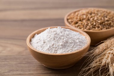 Tahta masadaki buğday unu ve buğday taneleri, yiyecek malzemesi.