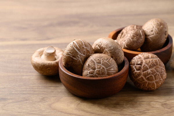 Fresh shiitake mushroom in bowl on wooden background, edible mushroom and food ingredient in Asian cuisine