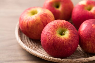 Ahşap zemin üzerinde kırmızı elma (kıskanç elma) sepeti