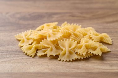 Ahşap zemin üzerinde pişirilmemiş farfalle makarna (papyon şekli), İtalyan yemek malzemesi