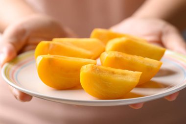 Elle tutulan, dilimlenmiş olgun hurma meyvesi, sağlıklı beslenme.