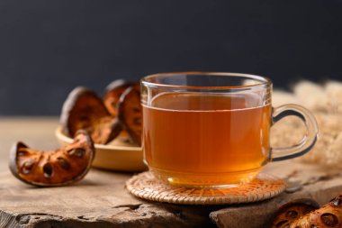 Bael meyveli bitkisel içecek bardakta, ahşap arka planda, sağlıklı içecek.