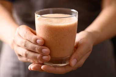 Elle tutulan bardakta portakallı yoğurt, sağlıklı meyve suyu.