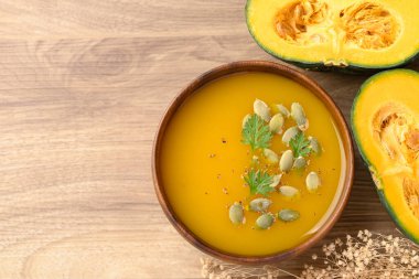 Tahta kasede balkabağı çorbası, sonbahar mevsiminde ev yapımı yemekler, masa üstü manzarası.